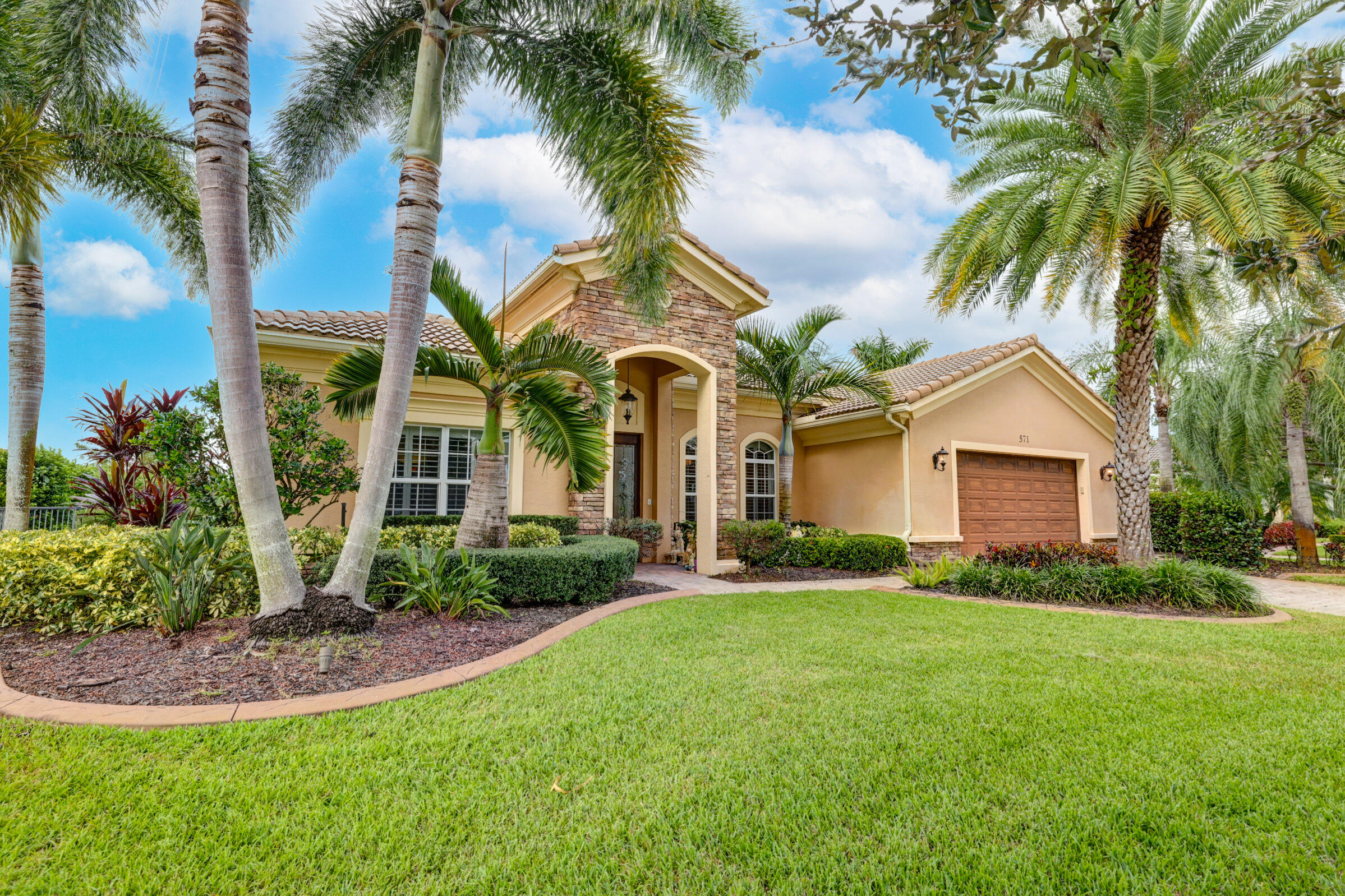 571 Southeast Tres Belle Circle Stuart, FL 34997 - Photo 2 of 54 a front view of a house with a yard and palm trees