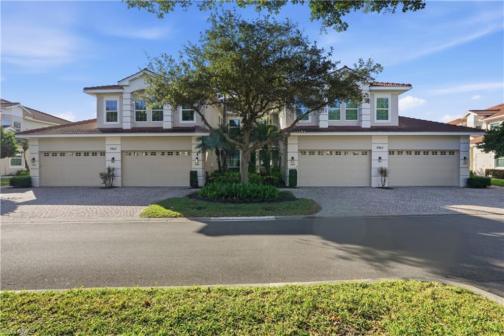 5963 Trophy Drive, Unit 2003 Naples, FL 34110 - Photo 2 of 50 Traditional-style house with a tile roof, decorative driveway, an attached garage, and stucco siding