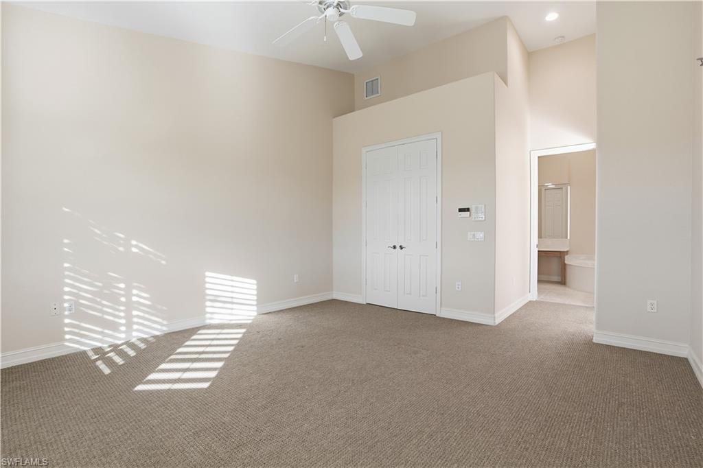 5963 Trophy Drive, Unit 2003 Naples, FL 34110 - Photo 33 of 50 Unfurnished bedroom featuring carpet, a closet, a ceiling fan, a towering ceiling, and ensuite bathroom