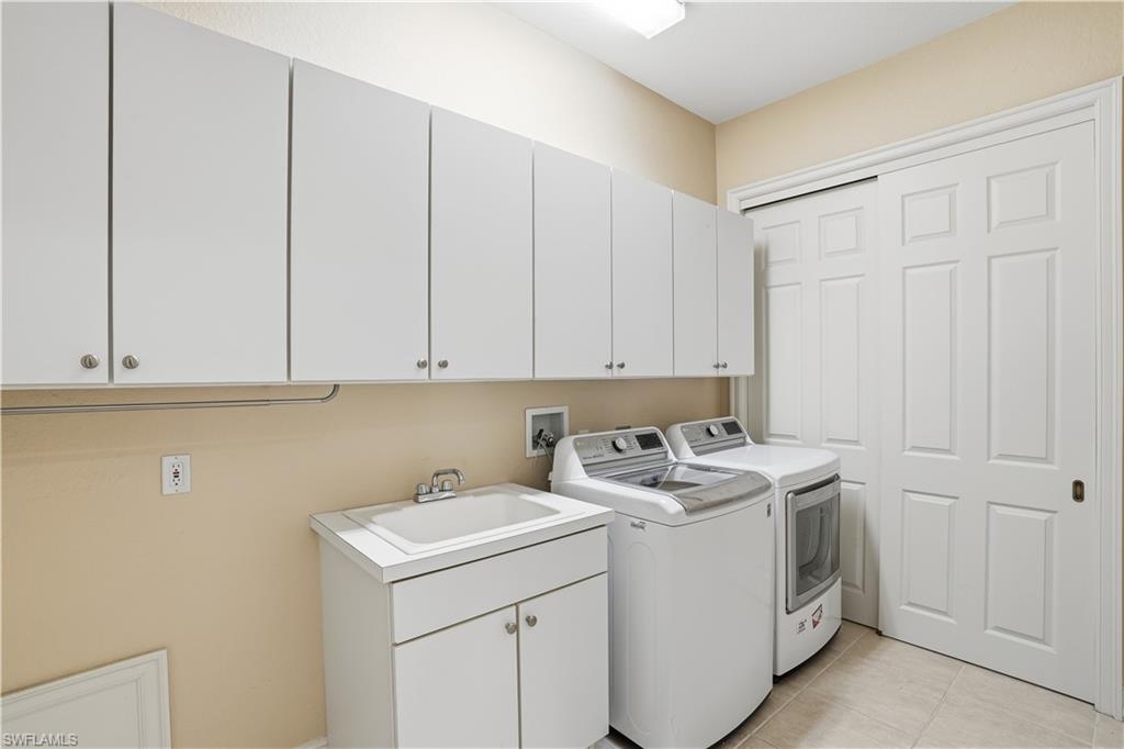 5963 Trophy Drive, Unit 2003 Naples, FL 34110 - Photo 45 of 50 Washroom featuring cabinet space, light tile patterned floors, and independent washer and dryer