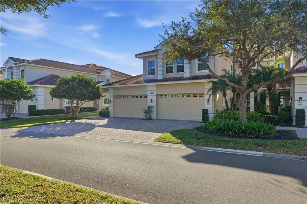 5963 Trophy Drive, Unit 2003 Naples, FL 34110 - Photo 48 of 50 View of front facade featuring decorative driveway, a tiled roof, an attached garage, and stucco siding