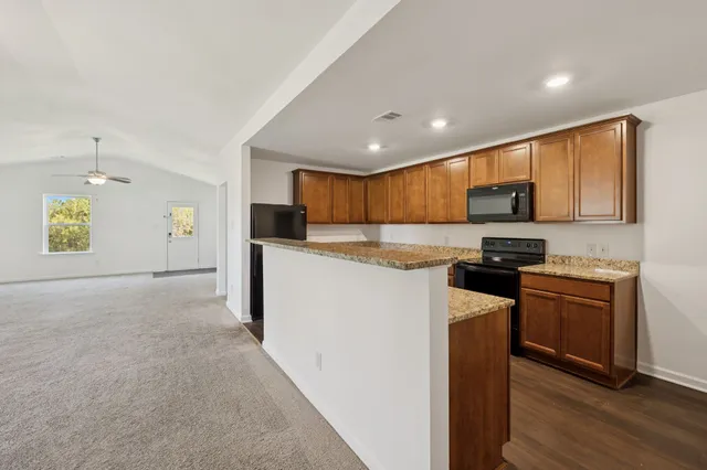 a kitchen with stainless steel appliances granite countertop a stove top oven a sink a refrigerator and white cabinets with wooden floor