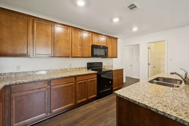 a kitchen with kitchen island granite countertop wooden cabinets and a refrigerator