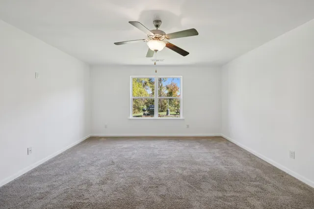 an empty room with windows and chandelier fan