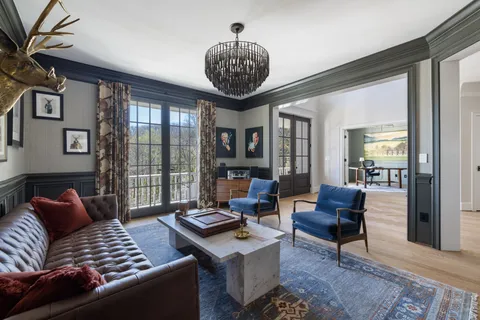 a dining room with wooden floor a chandelier a wooden table and chairs