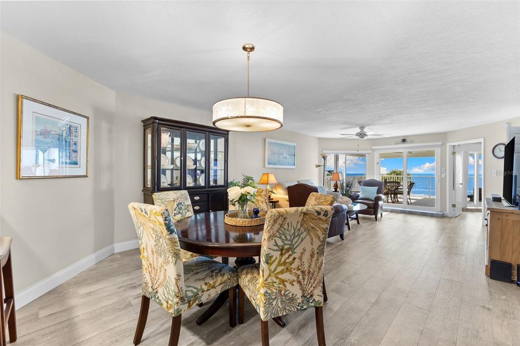 16332 Gulf Boulevard, Unit 2B Redington Beach, FL 33708 - Photo 11 of 60 a dining room with wooden floor a chandelier a wooden table and chairs