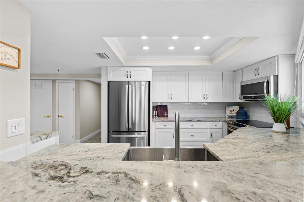 16332 Gulf Boulevard, Unit 2B Redington Beach, FL 33708 - Photo 21 of 60 a kitchen with stainless steel appliances kitchen island granite countertop a refrigerator and a sink