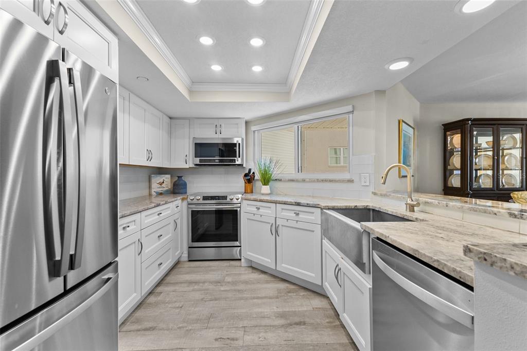 16332 Gulf Boulevard, Unit 2B Redington Beach, FL 33708 - Photo 24 of 60 a kitchen with stainless steel appliances granite countertop a stove top oven a sink and dishwasher