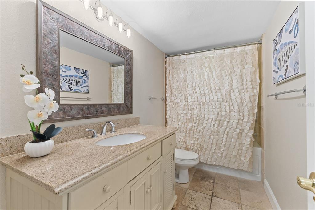 16332 Gulf Boulevard, Unit 2B Redington Beach, FL 33708 - Photo 33 of 60 a bathroom with a granite countertop sink a toilet and a mirror