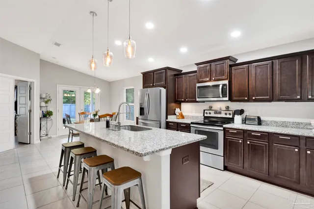 a kitchen with stainless steel appliances granite countertop a stove top oven a sink dishwasher a dining table and chairs