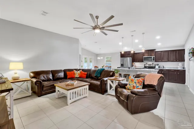 a living room with furniture kitchen view and a chandelier