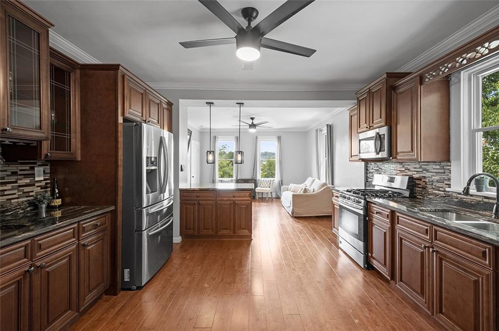 1815 Main Street Bridgeville, PA 15017 - Photo 5 of 32 a kitchen with refrigerator a stove a sink dishwasher a dining table and chairs with wooden floor