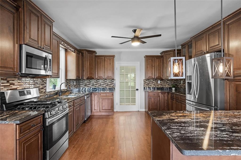 1815 Main Street Bridgeville, PA 15017 - Photo 8 of 32 a kitchen with stainless steel appliances granite countertop a stove top oven a sink dishwasher a refrigerator and cabinets with wooden floor