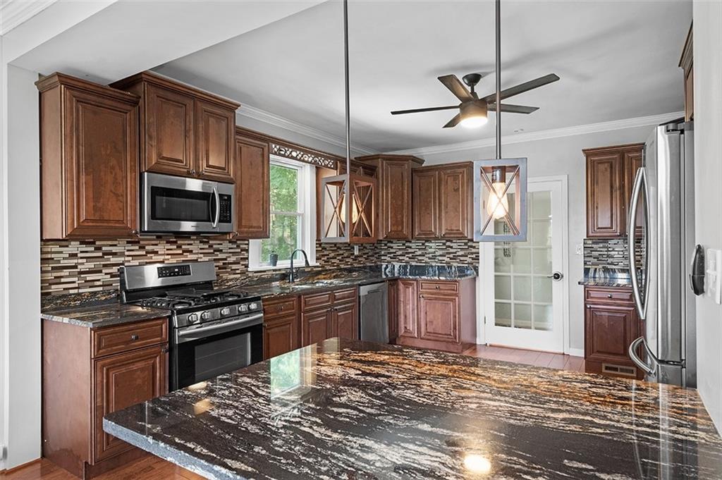 1815 Main Street Bridgeville, PA 15017 - Photo 9 of 32 a kitchen with stainless steel appliances granite countertop a stove top oven a sink dishwasher a refrigerator and cabinets with wooden floor