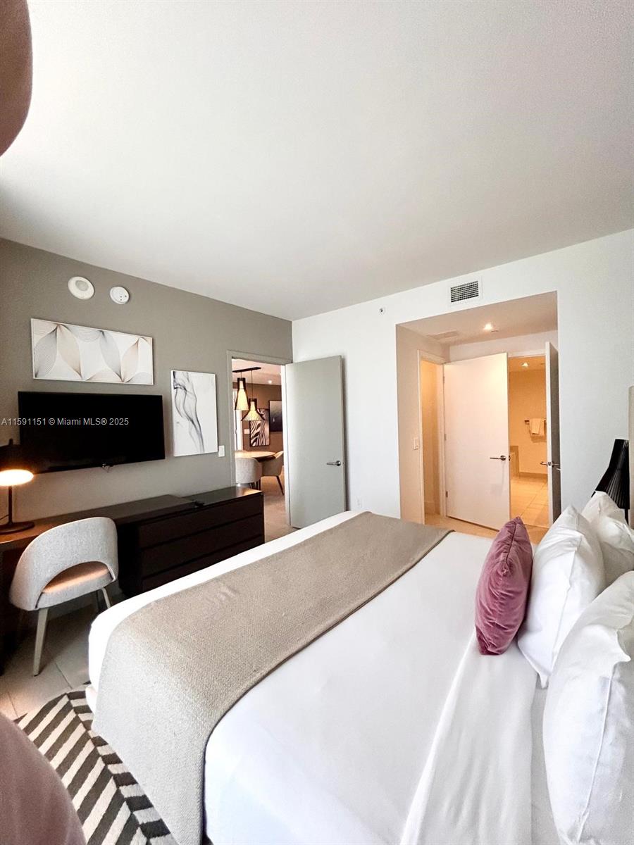 4010 South Ocean Drive, Unit R2407 Hollywood, FL 33019 - Photo 19 of 33 a bedroom with a bed and a lamp