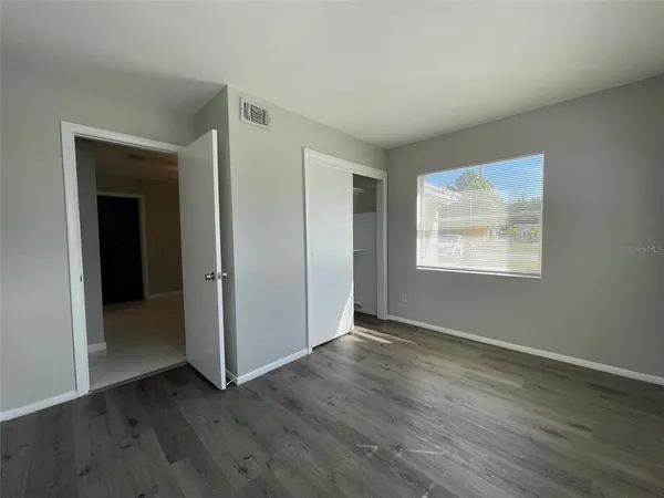 a view of an empty room with wooden floor and a window