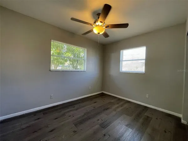 a view of wooden floor and a chandelier fan in a room