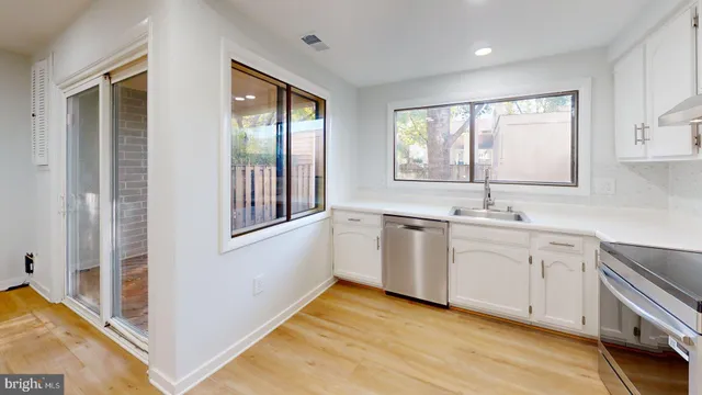 a view of a kitchen with dishwasher and white cabinets
