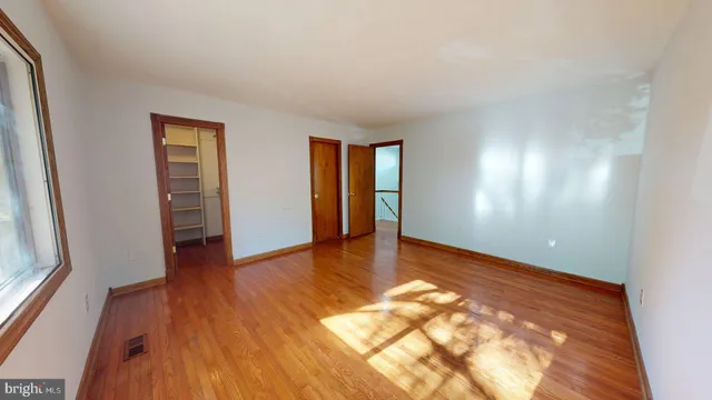 an empty room with wooden floor and windows