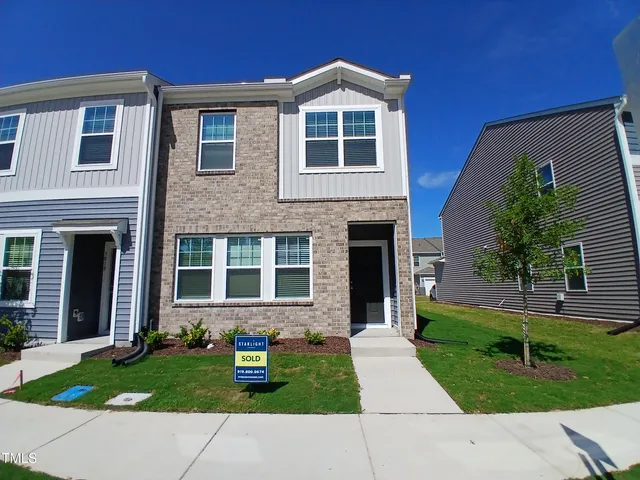 a sign that is sitting in front of a wooden house