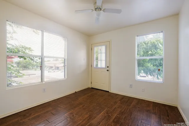 an empty room with wooden floor and windows
