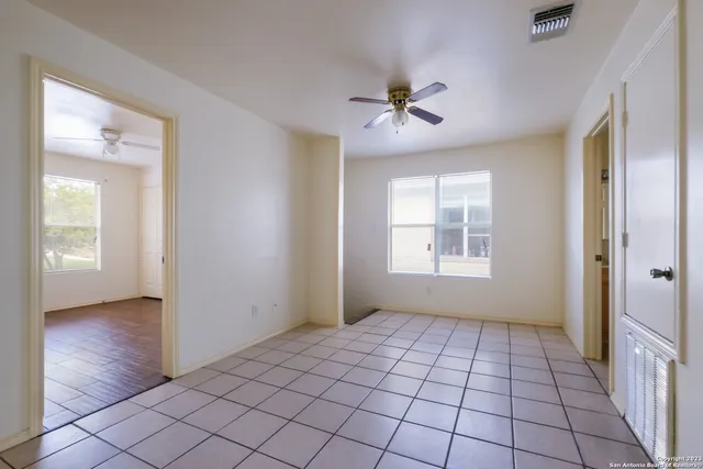 a view of an empty room with window and chandelier fan