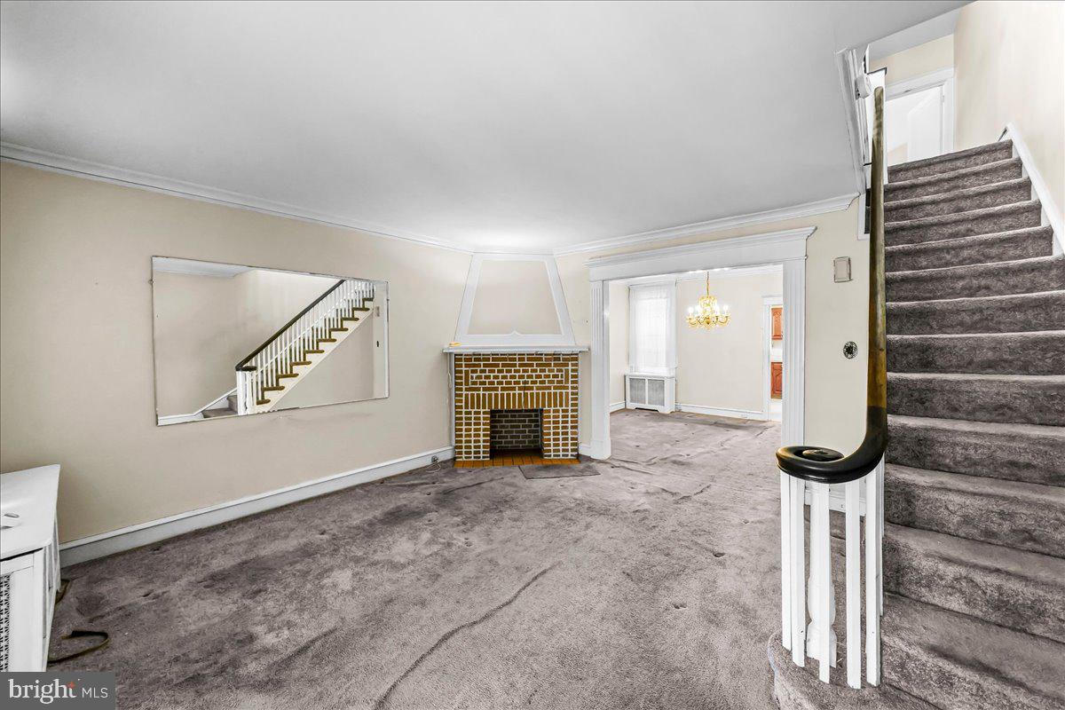 217 Avon Road Upper Darby, PA 19082 - Photo 4 of 16 a view of an empty room with chandelier fan and fire place