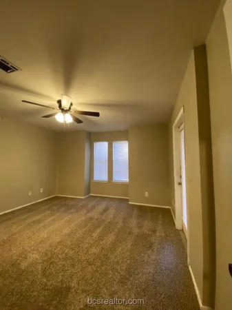 an empty room with windows and fan