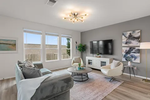 a living room with furniture a flat screen tv and a large window