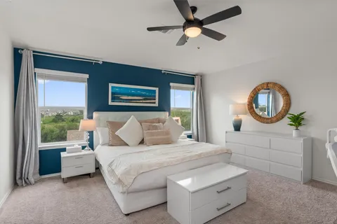 a bedroom with a large bed and a chandelier fan