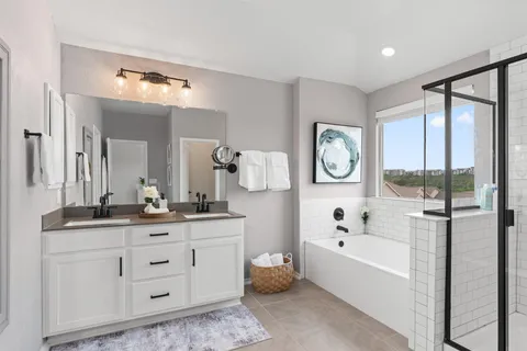 a bathroom with a tub a double vanity sink and a large mirror
