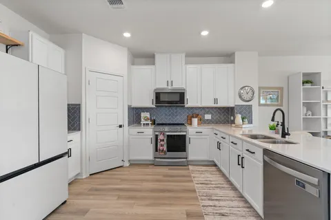 a kitchen with stainless steel appliances granite countertop a stove top oven a sink and a refrigerator
