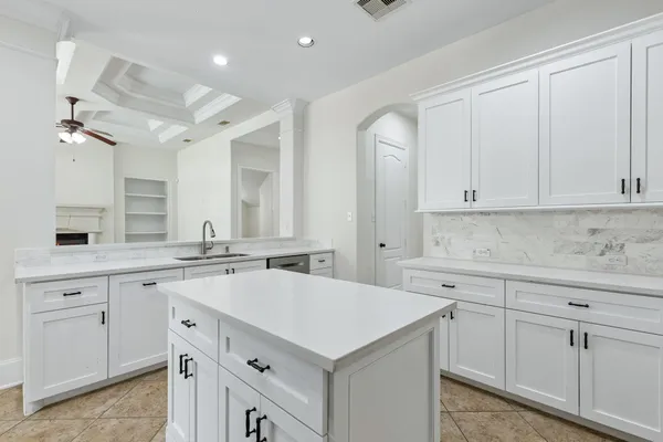 a kitchen with a sink dishwasher and white cabinets with wooden floor