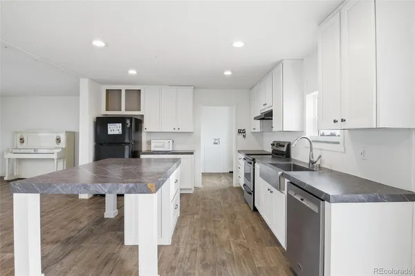 a large kitchen with stainless steel appliances granite countertop a lot of counter space and wooden floors