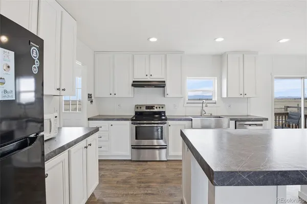 a kitchen with stainless steel appliances granite countertop a stove top oven a sink and white cabinets