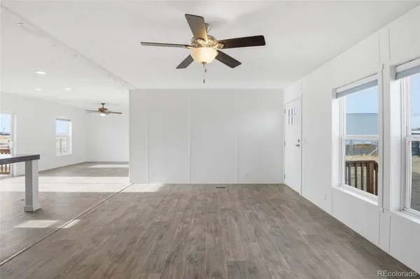 a view of an empty room with window and wooden floor