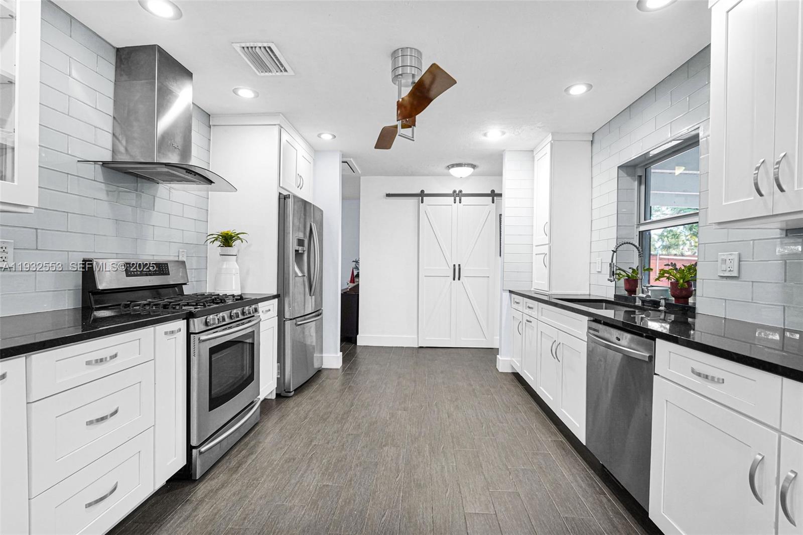 11561 Southwest 121st Avenue Miami, FL 33186 - Photo 24 of 30 a kitchen with stainless steel appliances a sink dishwasher a refrigerator and white cabinets with wooden floor