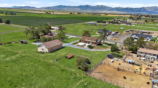 4468 North Droubay Road Tooele, UT 84074 - Photo 50 of 60 Expansive green spaces, multiple outbuildings, and a large residential structure with a light-colored roof