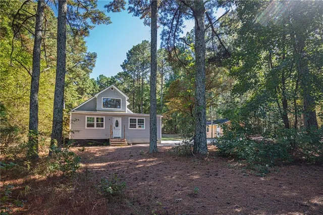 a front view of a house with a yard and large trees