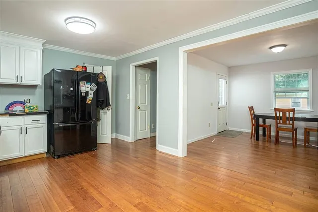 a view of a kitchen with refrigerator and wooden floor