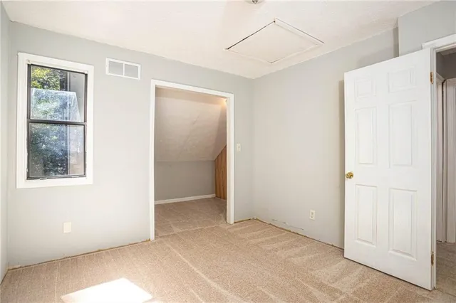 a view of an empty room with closet and a window