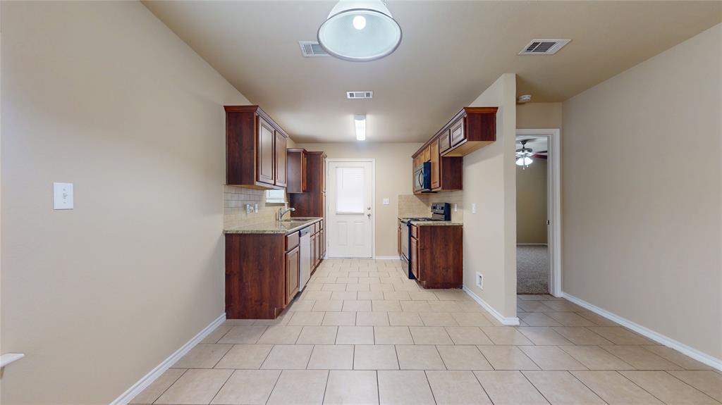 812 Parkplace Ridge Princeton, TX 75407 - Photo 4 of 17 Kitchen featuring backsplash, stainless steel appliances, light tile patterned floors, wood finish cabinets, and light stone counters