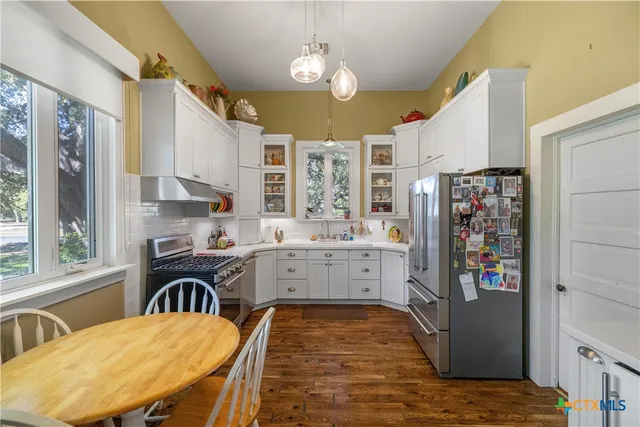 a kitchen that has a table chairs in it and wooden floors