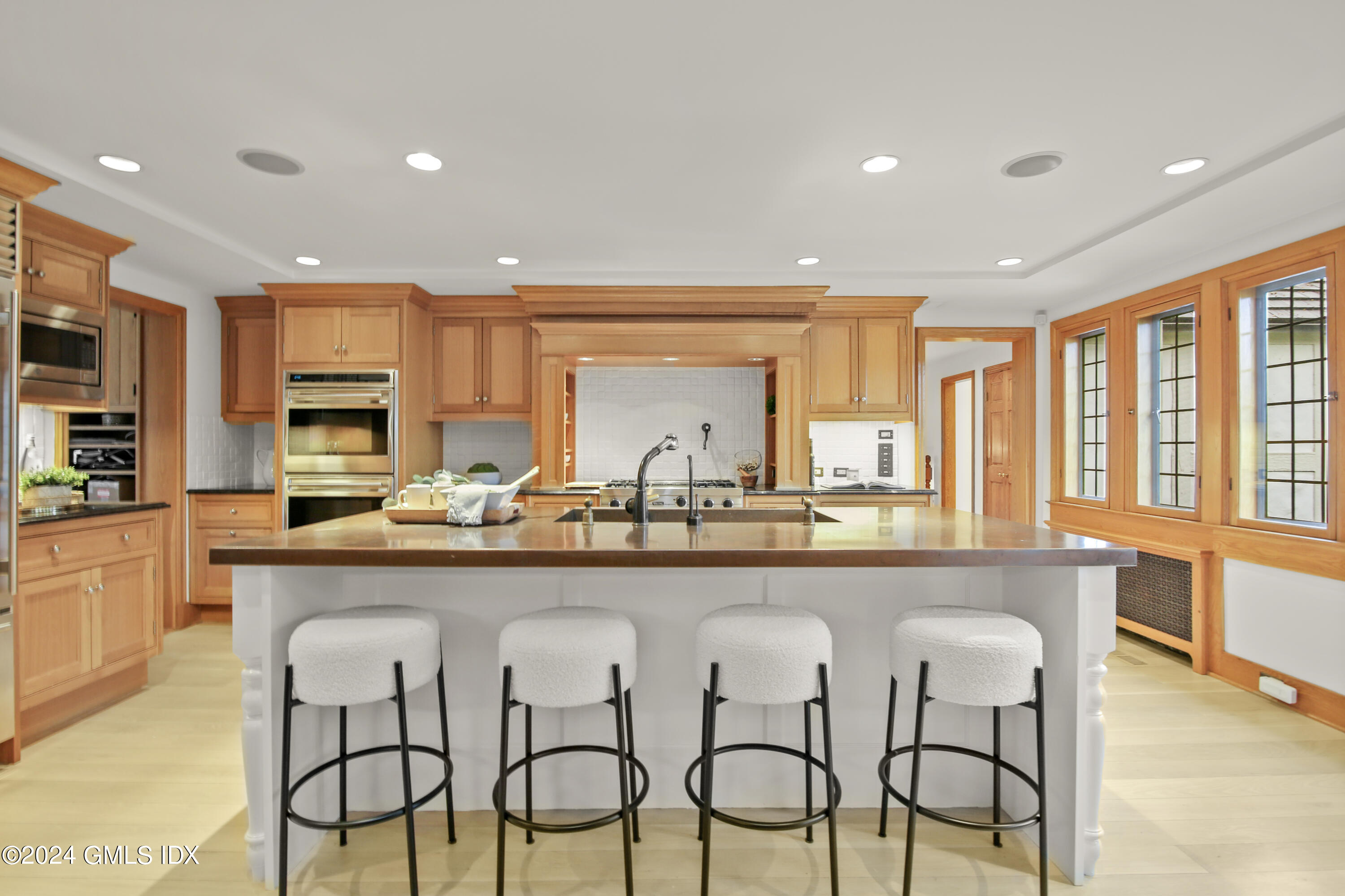 528 Field Point Road Greenwich, CT 06830 - Photo 11 of 31 a large kitchen with granite countertop a dining table chairs wooden cabinets and stainless steel appliances