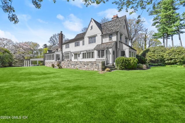 a view of a big house with a big yard plants and large trees