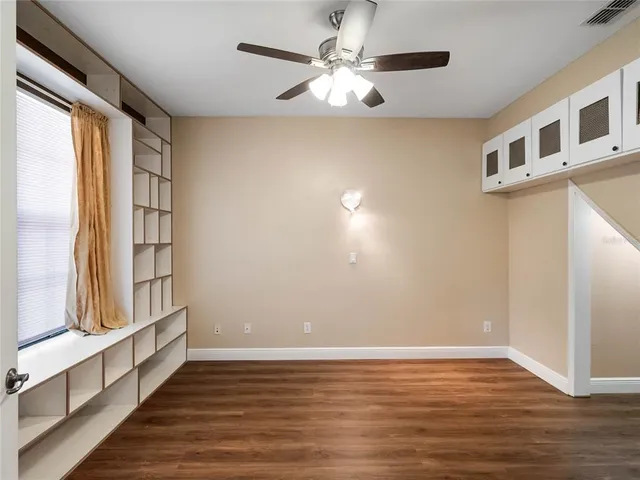 a view of an empty room with wooden floor and windows