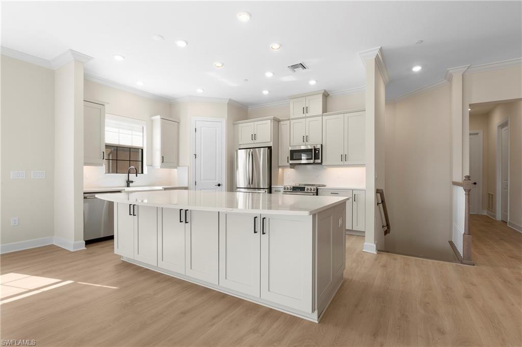 15327 Lucerna Street, Unit 204 Naples, FL 34114 - Photo 17 of 45 a large white kitchen with kitchen island a sink a center island stainless steel appliances and a window