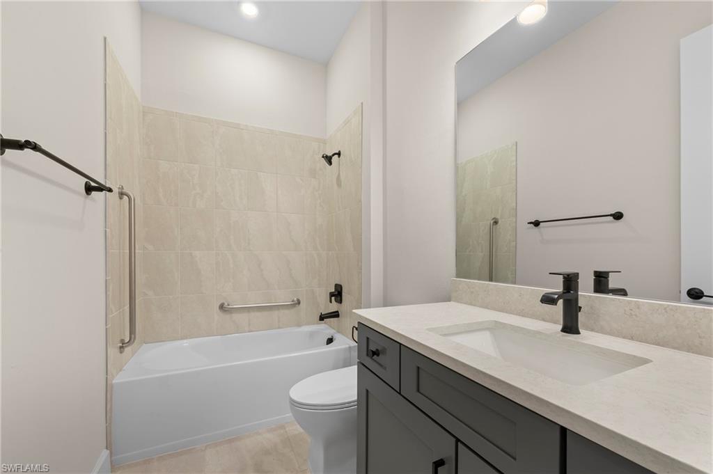 15327 Lucerna Street, Unit 204 Naples, FL 34114 - Photo 29 of 45 a bathroom with a granite countertop sink a toilet a mirror a bathtub and shower