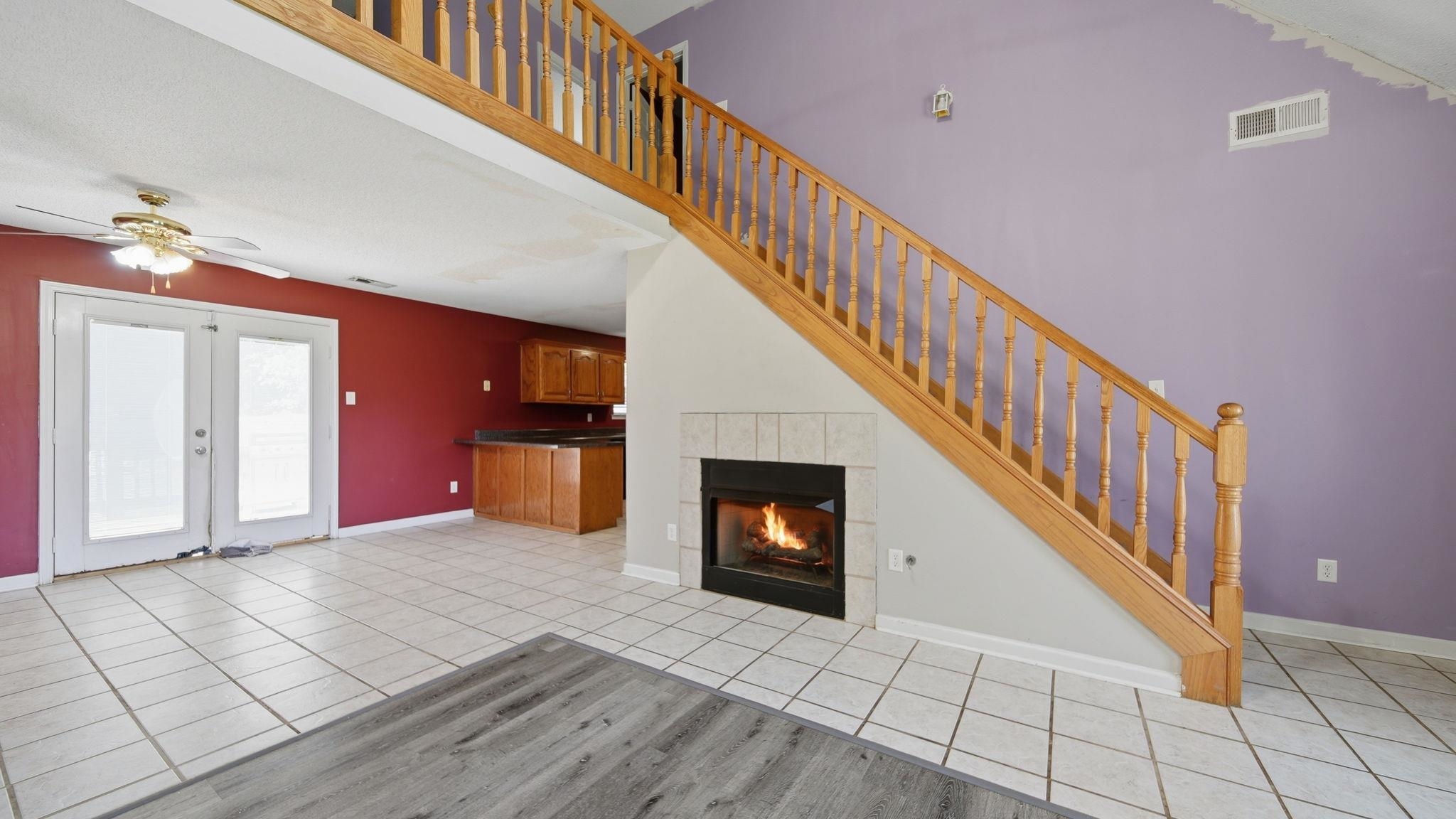 217 Rae Drive Munford, TN 38058 - Photo 9 of 40 Two-story ceiling with fireplace, with gas logs, wood staircase, and tile flooring.