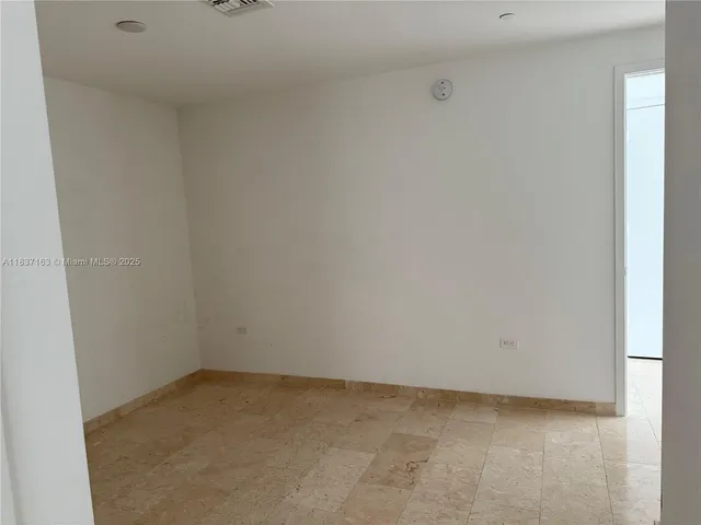 an empty room with wooden floor and windows with curtains
